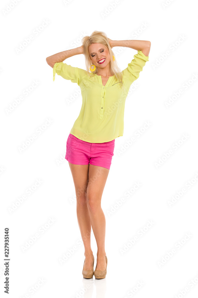 Blond Woman In Vibrant Clothes Is Standing With Eyes Closed And Holding Head In Hands Blond Woman In Vibrant Clothes Is Standing With Eyes Closed And Holding Head In Hands