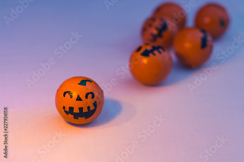 Chocolates of small orange Halloween pumpkins on a white and colorful background