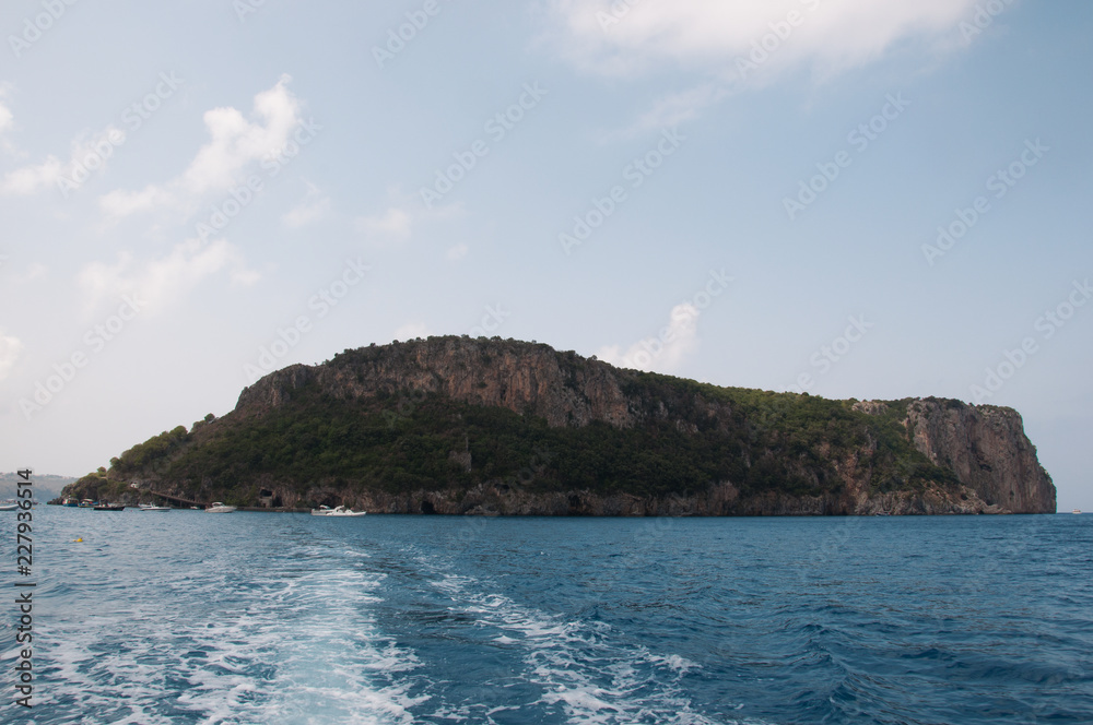 Isola in mezzo al mare e scia della barca. Calabria, Sud Italia.