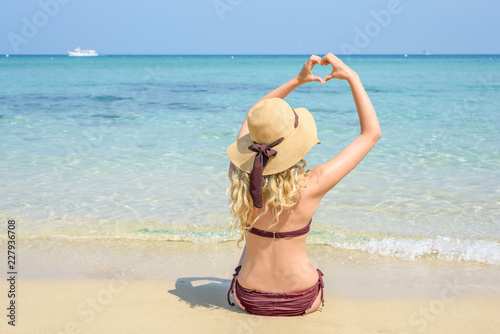 Woman at the beach in Cyprus. Love heart shape with hands. Beautiful Summer s...
