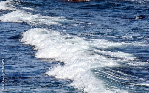 side view of white capped waves on the blue ocean surface 