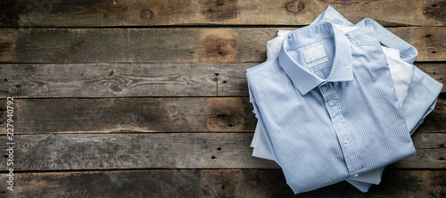 Stack of male folded shirts on rustic background, top view
