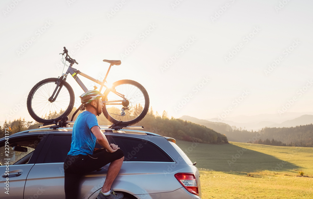 Naklejka premium Man came by auto in mountain with his bicycle on the roof. Mountain biking concept