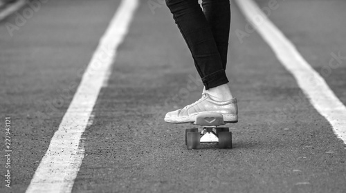 Teenage Skateboarding. Young girl wearing in black jeans and gumshoes riding on a skateboard on a stadium running track.