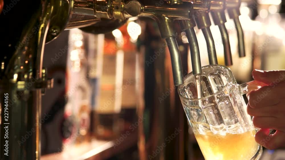 Turning off beer tap after filling glass. Man Pouring full glass of draft beer, then turning off the tap.