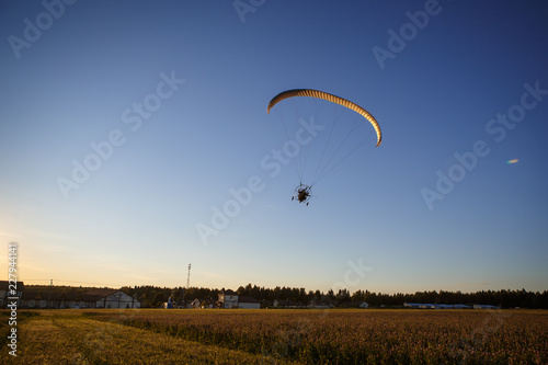 Paratrayke flight, paraglider in the sky at sunset. The wing of a parachute with a paraglider cabin flies across the sky in the setting sun