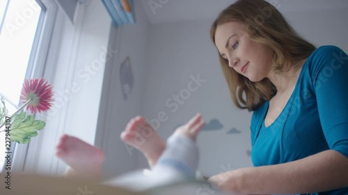 Young caucasian mother changing her baby's nappy photo