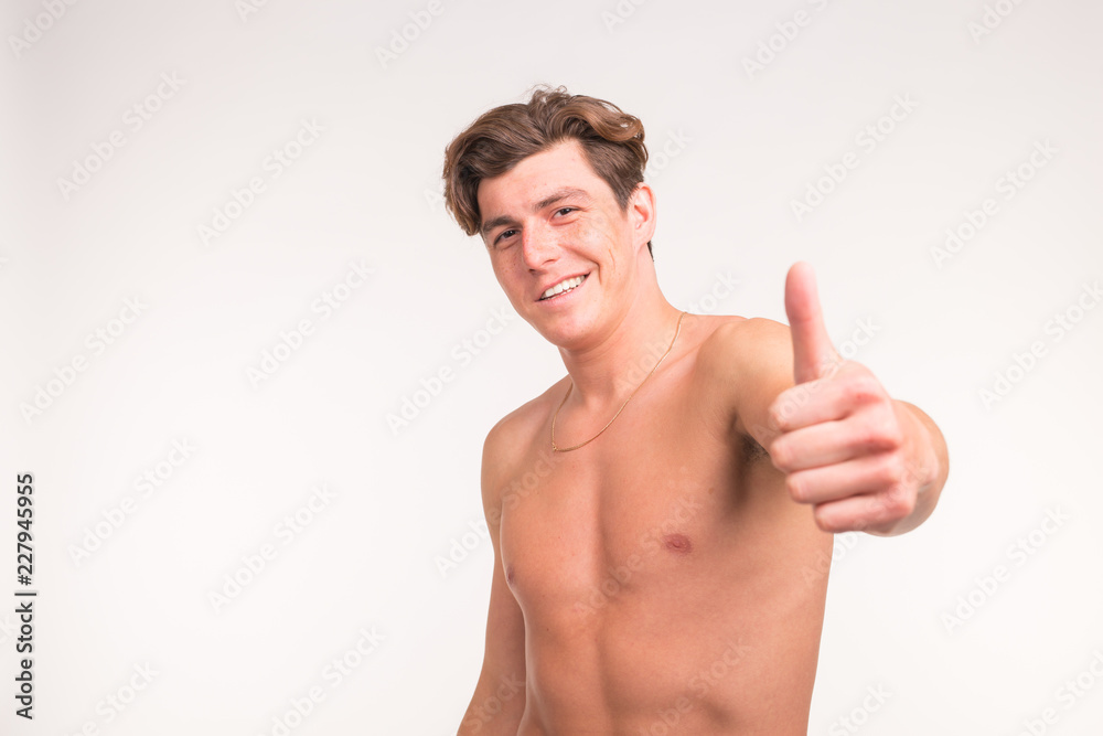 People, gesture, fitness and sport concept - athletic shirtless man showing thumb up over white background People, gesture, fitness and sport concept - athletic shirtless man showing thumb up over white background