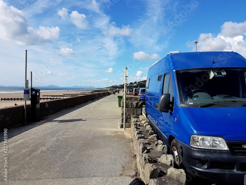 A view down Barmouth promenade with blue van and cars parked. photo