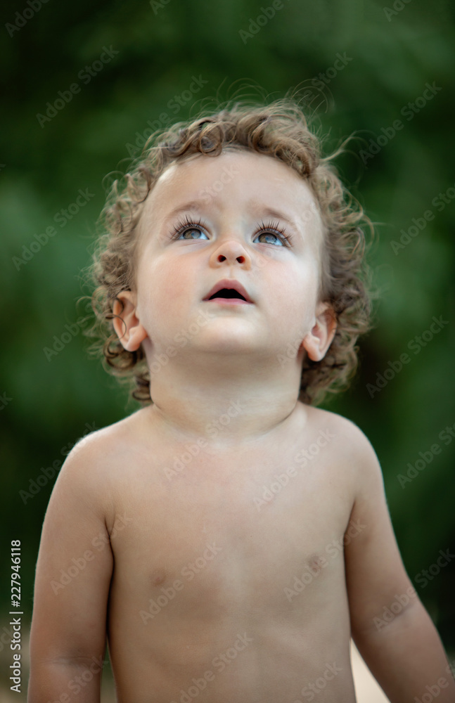 Beautiful baby with curly hair in the garden Beautiful baby with curly hair in the garden