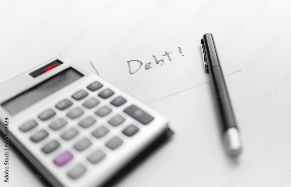 calculator with a pen and paper note with debt word isolated on white background calculator with a pen and paper note with debt word isolated on white background