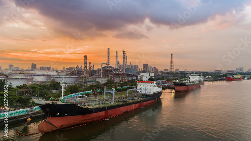 Oil tanker wirh Oil refinery factory background at dawn for energy or gas industry background.