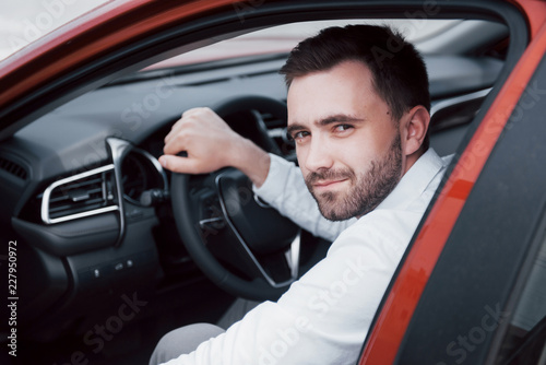 Confident young businessman sitting at the wheel of his new car