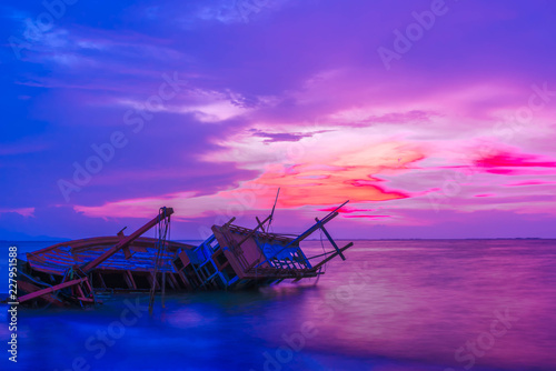 Broken fishing boat on seacoast in sunset, Thailand.