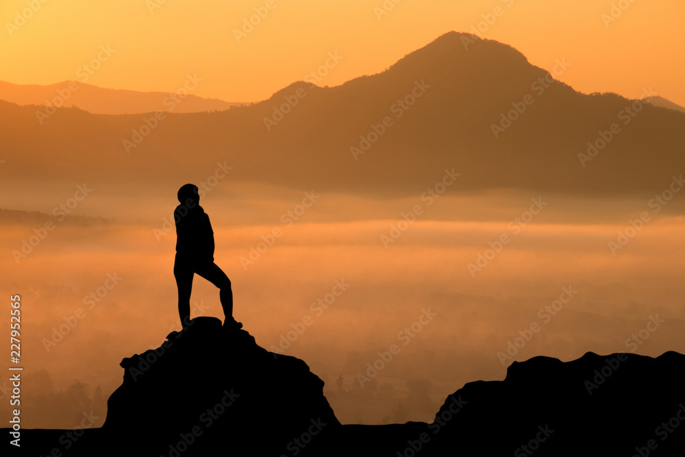 silhouette of a man standing on the mountains with sunrise in the morning.