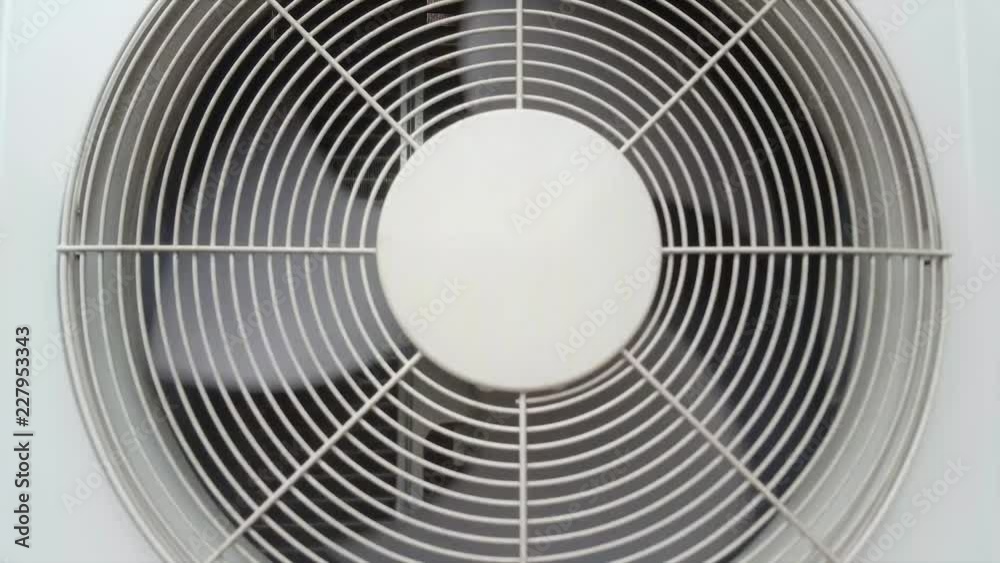 Front view of an air conditioning condenser unit with its fan spinning around