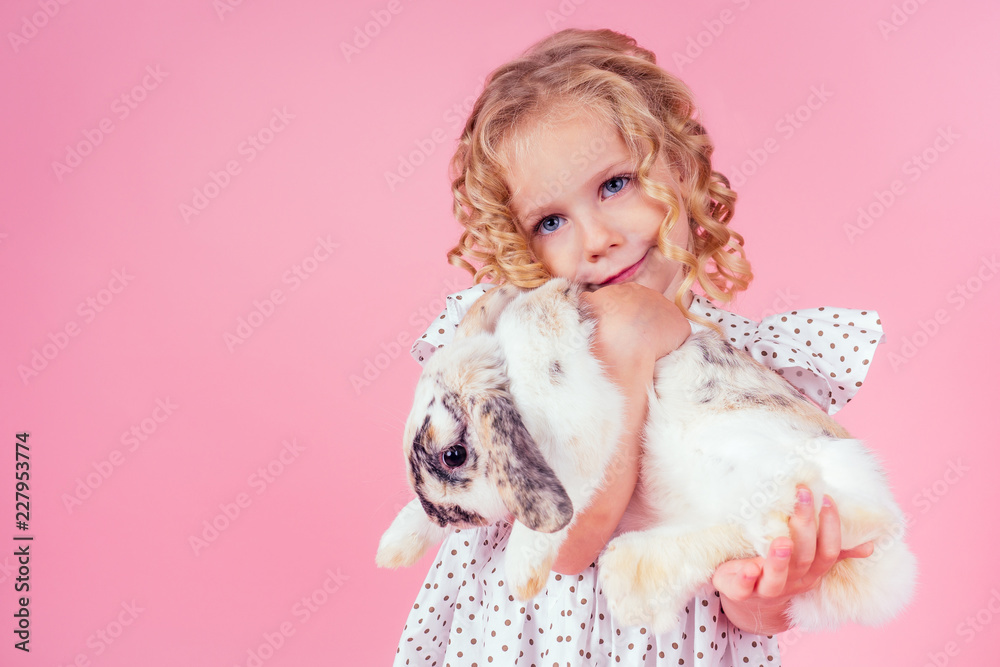 little blonde girl with a bunny rabbit easter in studio pink background.beautiful female kid celebrating Easter Holiday with pets,child painted eggs.dream and birthday present.Alice in Wonderland little blonde girl with a bunny rabbit easter in studio pink background.beautiful female kid celebrating Easter Holiday with pets,child painted eggs.dream and birthday present.Alice in Wonderland