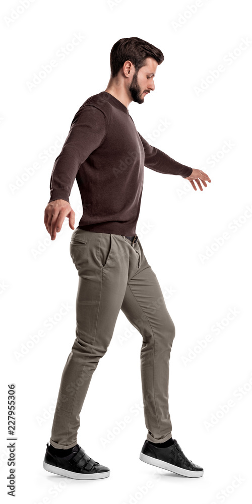 A fit man in casual clothes looks down as he lifts his foot during tightrope walking steps on a white background. A fit man in casual clothes looks down as he lifts his foot during tightrope walking steps on a white background.