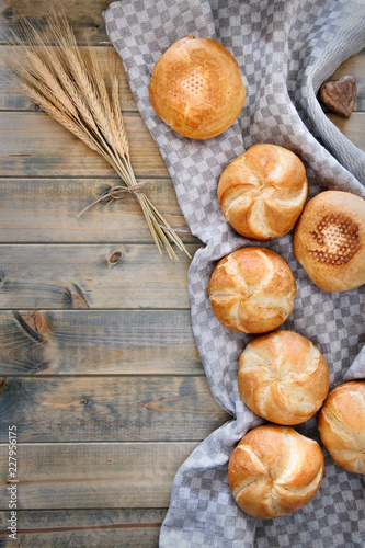 Crusty round bread rolls, known as Kaiser or Vienna rolls scattered on linen towel on rustic wood photo