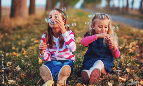 Billede på lærred Childhood time. Cute little girls makes a soap bubbles