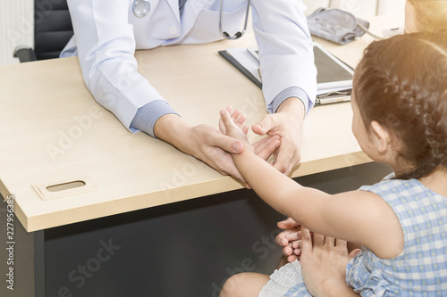 Pediatrician (doctor) man examining,reassuring and discussing kid in hospital room.Copy space.