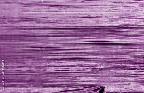 Crumpled transparent plastic surface in purple color.