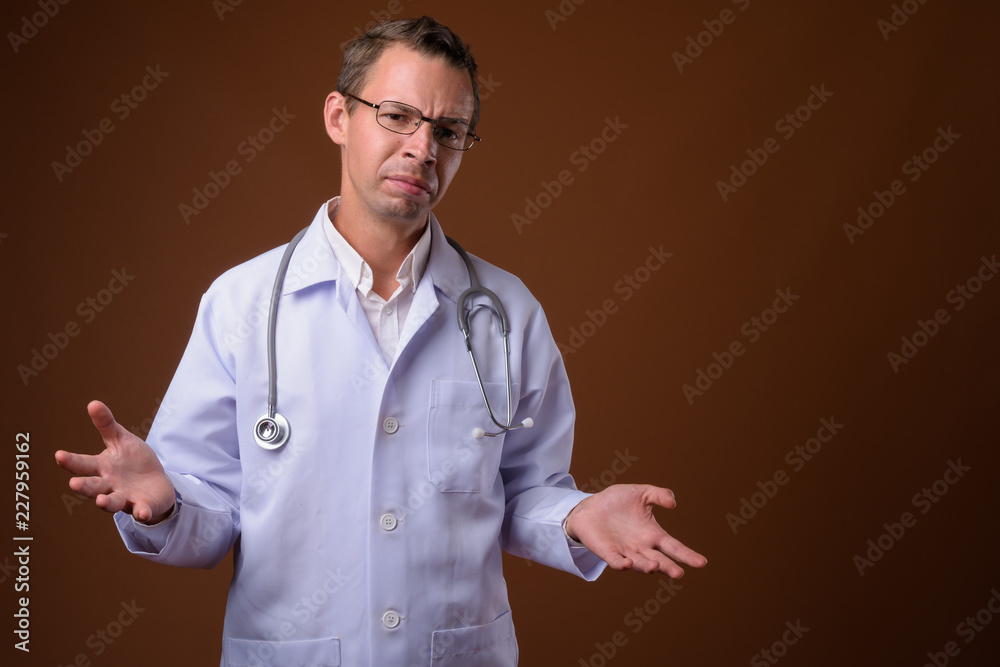 Studio shot of man doctor against brown background Studio shot of man doctor against brown background