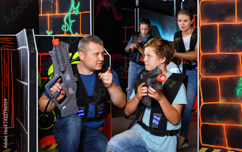 Happy teen boy with laser gun having fun on lasertag arena with his father © JackF