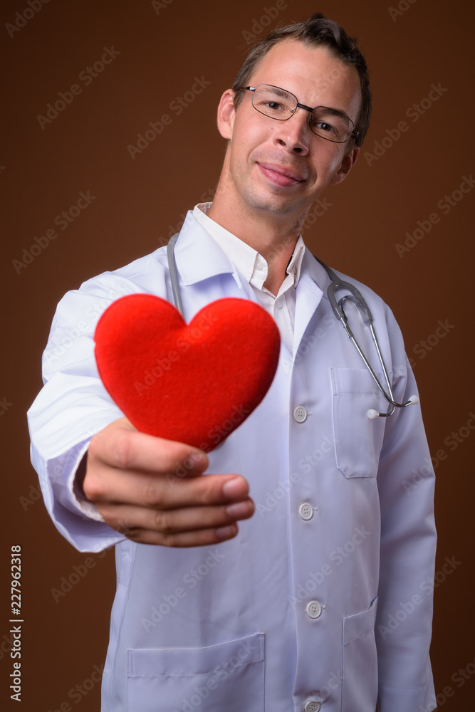 Studio shot of man doctor against brown background Studio shot of man doctor against brown background