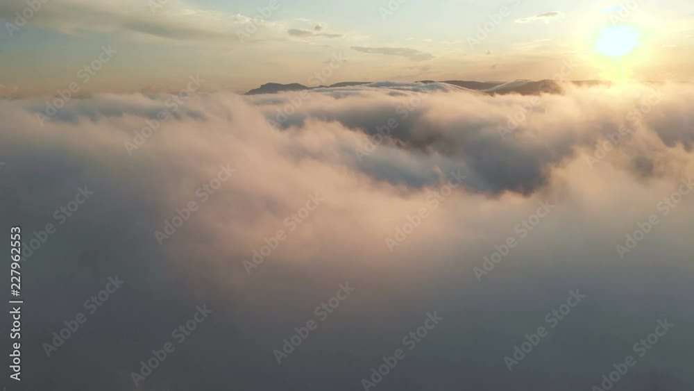 Flying through the clouds at dusk or dawn. Flying in pink clouds in the sun. Aerial view. North Caucasus Flying through the clouds at dusk or dawn. Flying in pink clouds in the sun. Aerial view. North Caucasus