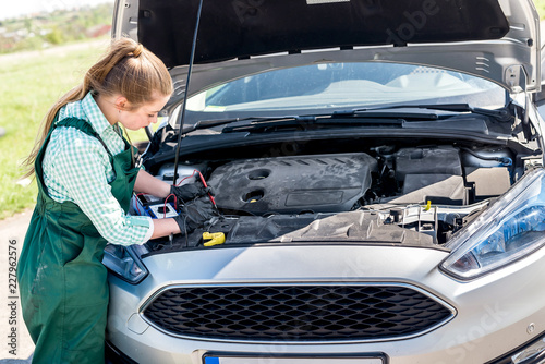 Mechanic - woman tests motor with tester