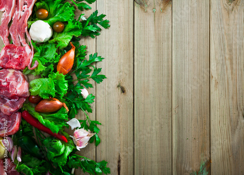 Raw lamb meat with vegetables on wooden background