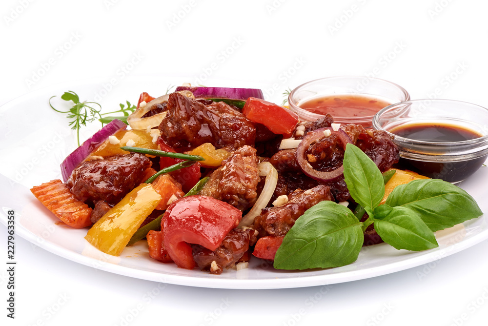 Roast Sweet and Sour Pork with vegetables in a plate with sauces, Chinese recipes WOK. Isolated on white background