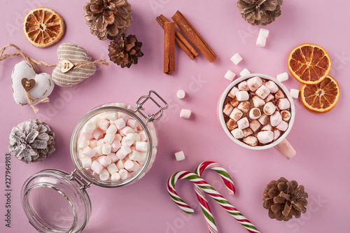 Top view of marshmallows in mug, glass jar and Christmas decoration on pink background