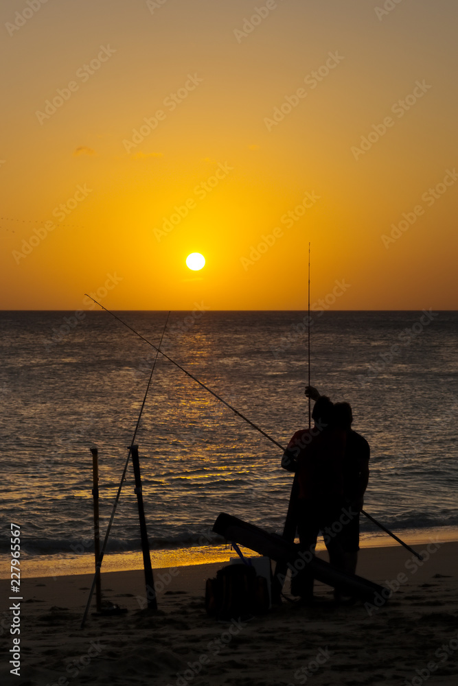 fishermen angler  with rod and reel  in  beach at sunset