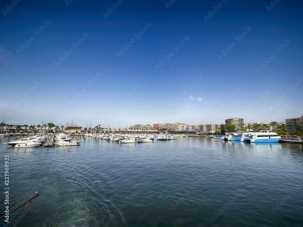 Port in Mediterranean sea. Sailing boats with a deflated sails near the sea pier.