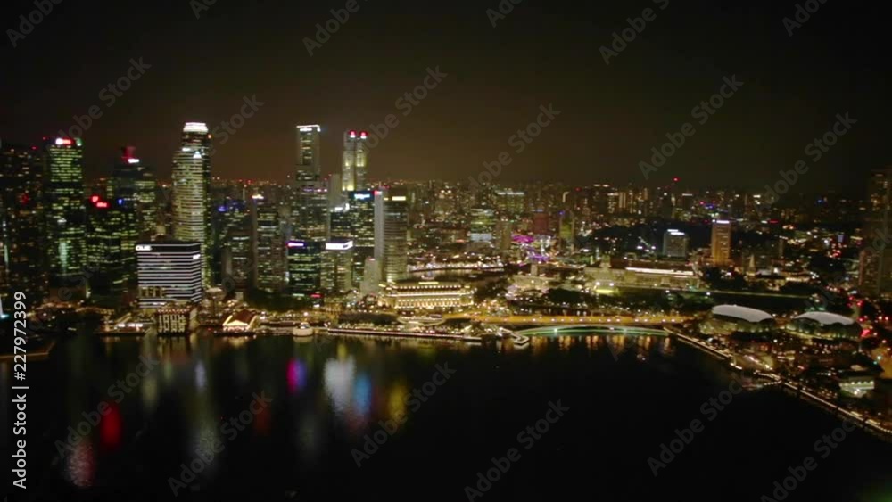 Aerial view of Singapore Marina Bay with Financial District skyscrapers illuminated at night reflected on the harbor. Rooftop above Singapore skyline. Night urban scene. Aerial view of Singapore Marina Bay with Financial District skyscrapers illuminated at night reflected on the harbor. Rooftop above Singapore skyline. Night urban scene.