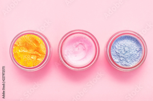 Jars of body cream on color background