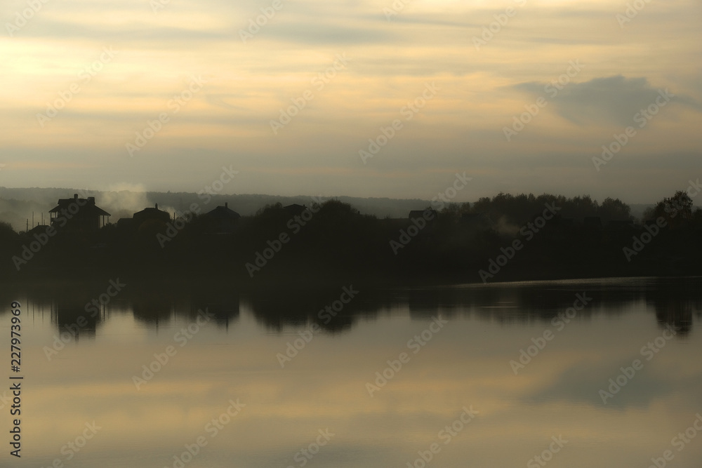 Autumn landscape with the image of a lake at sunset