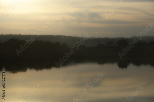 Autumn landscape with the image of a lake at sunset