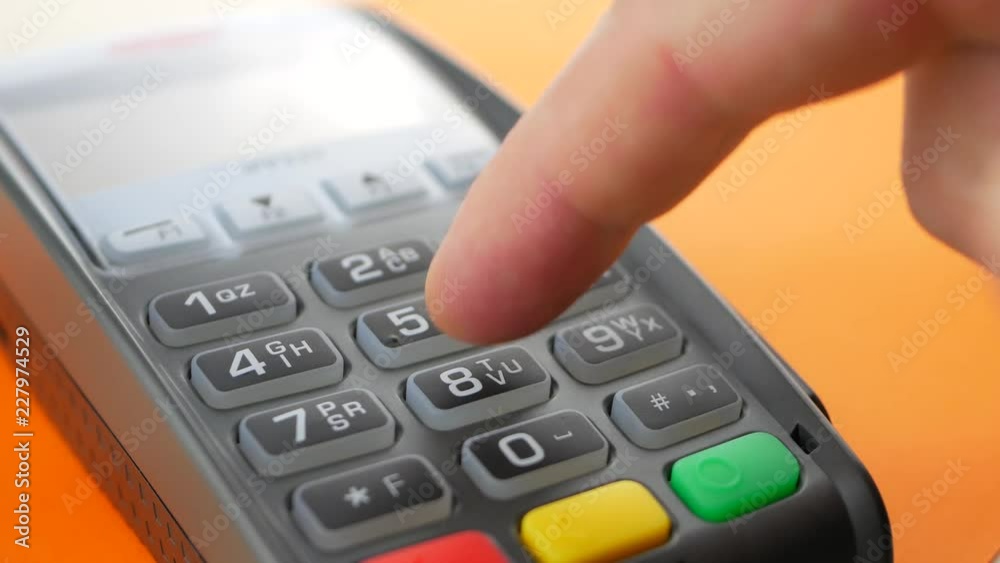 Customer paying a merchant with mobile phone with NFC technology at orange background. Finger entering the PIN code Customer paying a merchant with mobile phone with NFC technology at orange background. Finger entering the PIN code