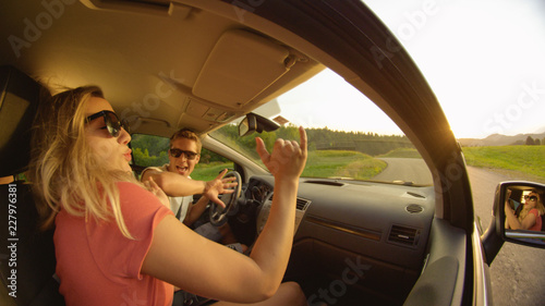 CLOSE UP: Side view of a young couple dancing in their car while they drive. © helivideo