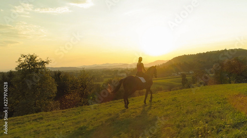 AERIAL Unrecognizable young woman riding her brown horse through the countryside © helivideo