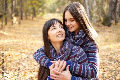 Cute portrait of mother and daughter in the autumn forest.