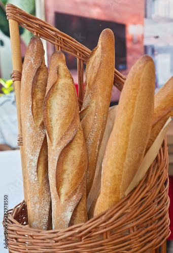Front view, medium distance of a wood, weaved basket of freshly baked baguettes on display and for sale at a tropical, autumn, farmers market