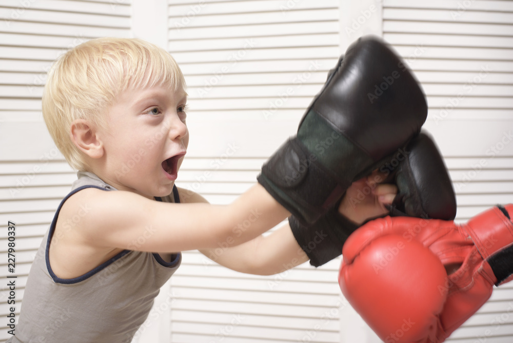 Blond boy boxing with hand in red glove. Emotions