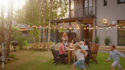 Big Family Garden Party Celebration, Gathered Together at the Table Family, Friends and Children. People are Drinking, Passing Dishes, Joking and Having Fun. Panoramic Camera Shot. photo