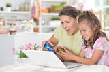 portrait of cute little girl with young mother playing computer 