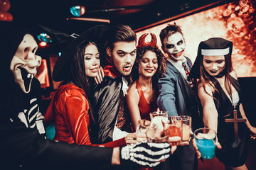 Friends in Halloween Costumes Drinking Cocktails