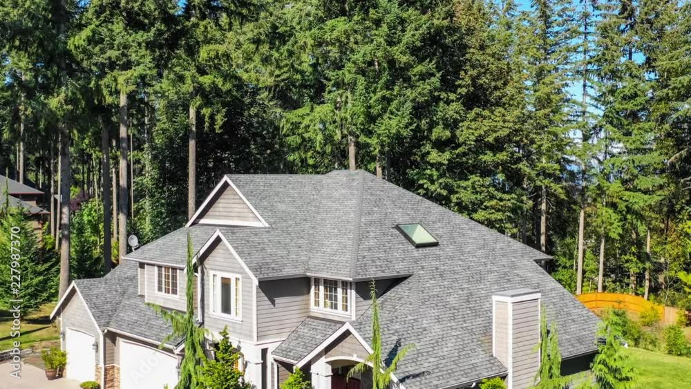 4k footage of an aerial fly-over of a luxury American suburban home in a heavily wooded area